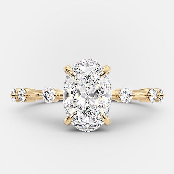 An elongated oval solitaire dainty pave moissanite engagement ring with a gold band.