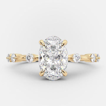 An elongated oval solitaire dainty pave moissanite engagement ring with a gold band.
