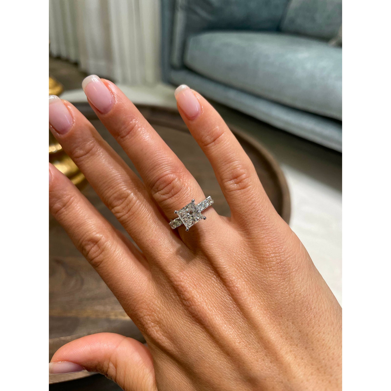 A princess cut diamond pavé engagement ring with gold band and round moissanite side stones